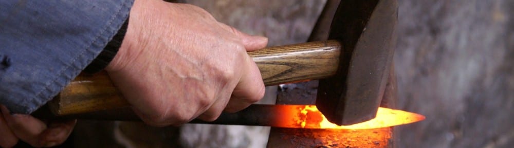 Hammering hot metal on an anvil in a forge